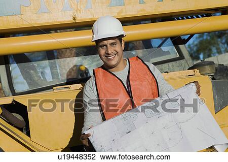 Stock Image - Builder with blueprint for new home, portrait. Fotosearch