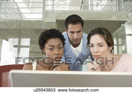 Stock Image - Business colleagues using laptop in office. Fotosearch