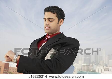 Picture - Business man checking watch on city street. Fotosearch