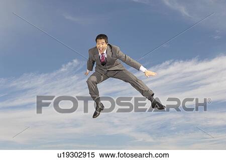 Stock Photography - Business man crouching mid-air outdoors. Fotosearch
