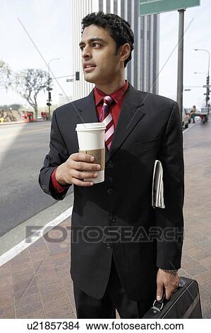 Picture - Business man holding take-out coffee cup on city street. Fotosearch