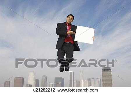 Business man jumping with blank sign above city View Large Photo Image Stock Image - Business man jumping with blank sign above city. Fotosearch