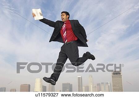 Stock Photo - Business man jumping with newspaper over city. Fotosearch