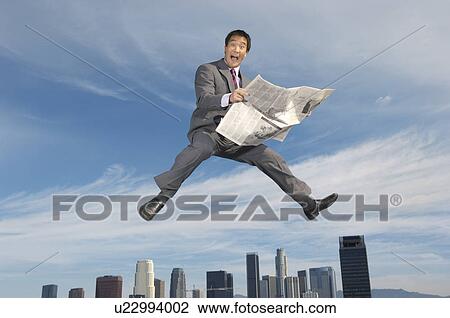 Stock Image - Business man reading newspaper mid-air above city. Fotosearch