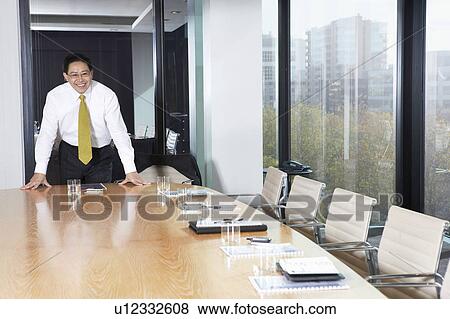 Business man standing behind table in boardroom View Large Photo Image Stock Photo - Business man standing behind table in boardroom. Fotosearch