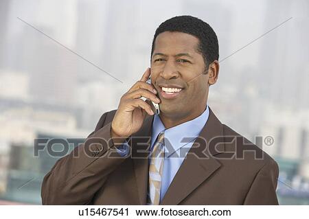 Stock Image - Business man using mobile phone outdoors. Fotosearch