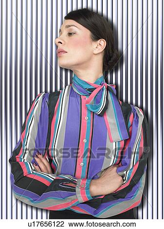 Stock Image - Business woman with arms crossed in front of stripy background. Fotosearch