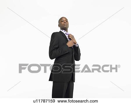 Businessman adjusting tie in studio View Large Photo Image Stock Photo - Businessman adjusting tie in studio. Fotosearch