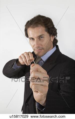 Stock Photo - Businessman aiming rubber band, on white background, portrait. Fotosearch