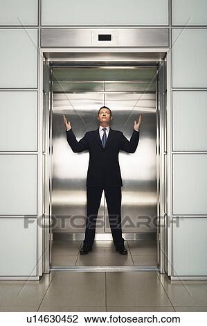 Businessman arms raised in Elevator, front view View Large Photo Image Stock Image - Businessman arms raised in Elevator, front view. Fotosearch