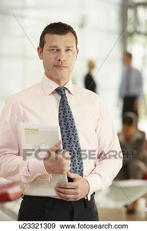 Stock Photo - Businessman Holding Report in office, portrait. Fotosearch