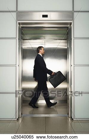 Stock Photography - Businessman in Elevator with briefcase, side view. Fotosearch