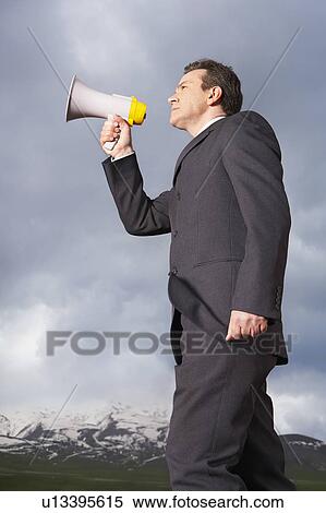 Businessman in mountain field Speaking Through Megaphone, low angle view View Large Photo Image Stock Photography - Businessman in mountain field Speaking Through Megaphone, low angle view. Fotosearch