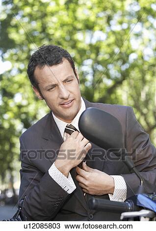 Businessman on motor scooter adjusting tie View Large Photo Image Stock Image - Businessman on motor scooter adjusting tie. Fotosearch