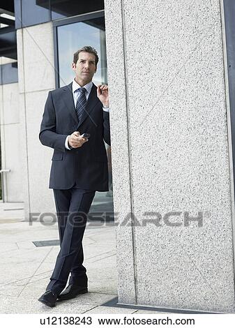 Stock Image - Businessman outside office building. Fotosearch