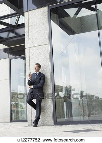 Stock Image - Businessman outside office building. Fotosearch
