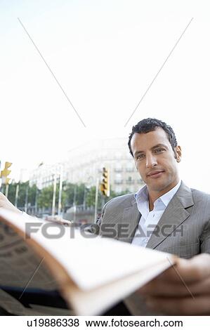 Stock Photo - Businessman reading newspaper, outdoors. Fotosearch