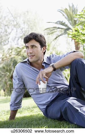 Businessman relaxing in park with coffee cup, portrait View Large Photo Image Stock Image - Businessman relaxing in park with coffee cup, portrait. Fotosearch