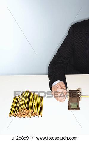 Businessman sharpening pencils at desk, mid section View Large Photo Image Stock Photo - Businessman sharpening pencils at desk, mid section. Fotosearch