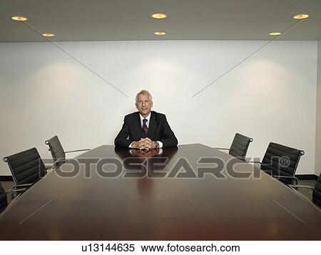 Businessman sitting alone in conference room View Large Photo Image Stock Photography - Businessman sitting alone in conference room. Fotosearch