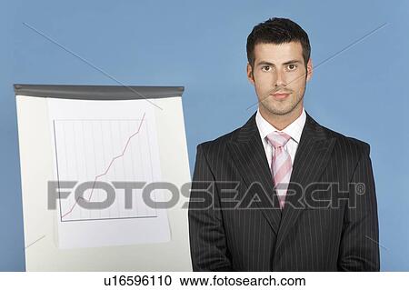 Stock Image - Businessman standing by flip chart, portrait. Fotosearch
