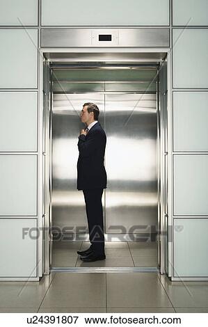 Stock Photo - Businessman Straightening Tie in Elevator, side view. Fotosearch