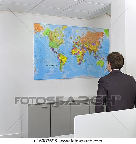 Stock Photograph - Businessman studying world map in office. Fotosearch