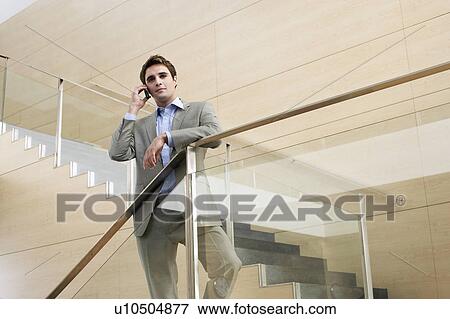 Stock Photo - Businessman talking on cell phone standing on stairs. Fotosearch