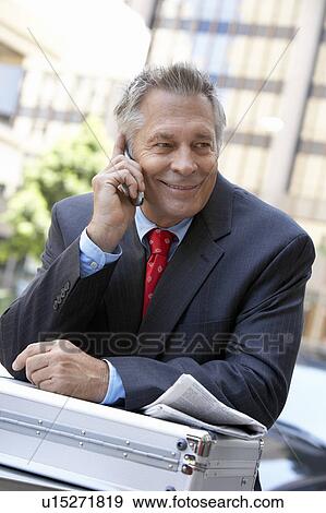Businessman using cell phone outdoors, half length View Large Photo Image Stock Photo - Businessman using cell phone outdoors, half length. Fotosearch