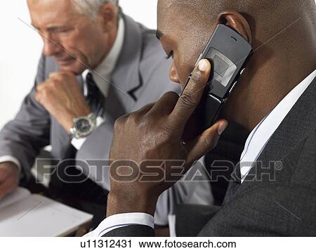 Businessman using mobile phone in meeting View Large Photo Image Stock Image - Businessman using mobile phone in meeting. Fotosearch