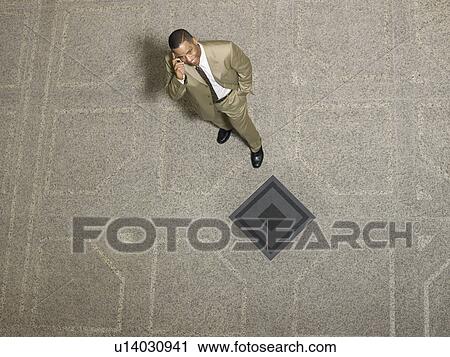 Stock Image - Businessman using mobile phone, indoors. Fotosearch