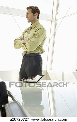 Stock Photo - Businessman with arms crossed in conference room. Fotosearch