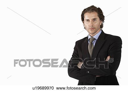 Stock Image - Businessman with arms crossed, on white background, portrait. Fotosearch