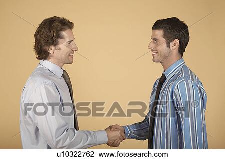Businessmen shaking hands, on plain background View Large Photo Image Stock Image - Businessmen shaking hands, on plain background. Fotosearch