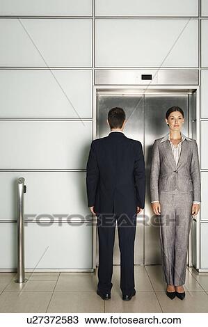 Stock Image - Businesspeople standing In and Out of Office Elevator. Fotosearch