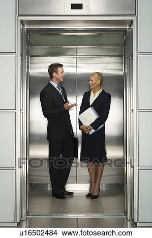 Picture - Businesspeople Talking in Elevator. Fotosearch