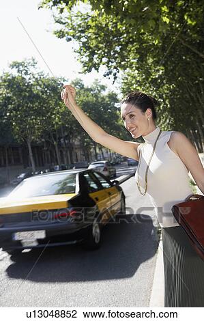 Businesswoman hailing taxi by road View Large Photo Image Stock Image - Businesswoman hailing taxi by road. Fotosearch