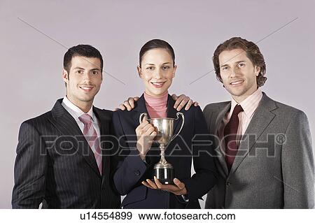 Businesswoman holding trophy with male colleagues, portrait View Large Photo Image Stock Photo - Businesswoman holding trophy with male colleagues, portrait. Fotosearch