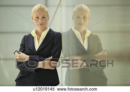 Stock Photography - Businesswoman Leaning Against Glass Partition. Fotosearch