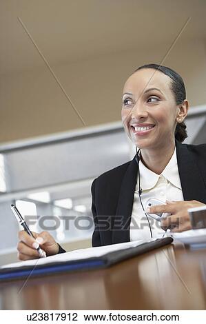 Businesswoman signing paperwork and using hands free kit View Large Photo Image Stock Image - Businesswoman signing paperwork and using hands free kit. Fotosearch