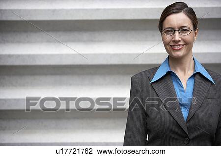 Businesswoman smiling, standing in front of wall, portrait View Large Photo Image Stock Image - Businesswoman smiling, standing in front of wall, portrait. Fotosearch