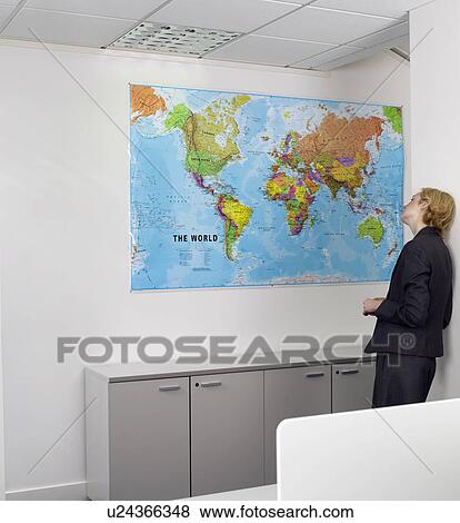 Stock Photo - Businesswoman studying world map in office. Fotosearch