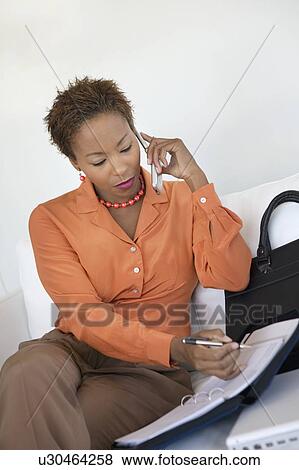 Stock Photo - Businesswoman Using Cell Phone and Organizer indoors. Fotosearch