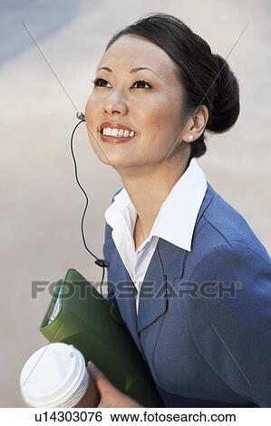 Stock Photograph - Businesswoman Using Cell Phone with hands free, outdoors. Fotosearch