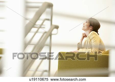 Stock Photography - Businesswoman waiting on sofa in office. Fotosearch