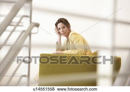 Stock Photo - Businesswoman waiting on sofa in office, portrait. Fotosearch