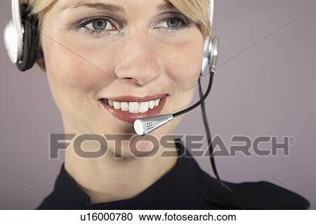 Stock Image - Businesswoman wearing headset, close-up, portrait. Fotosearch