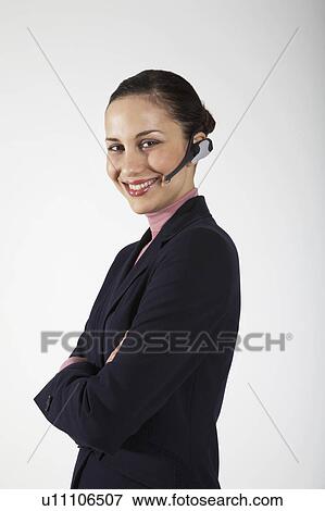 Stock Photo - Businesswoman wearing wireless headset, on white background, portrait. Fotosearch