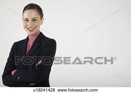 Stock Photo - Businesswoman with arms crossed, on white background, portrait. Fotosearch