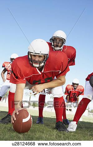 Stock Photo - Centre and Quarterback ready to hike football on field. Fotosearch